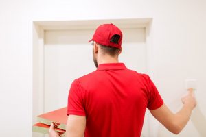 delivery man with pizza boxes ringing doorbell